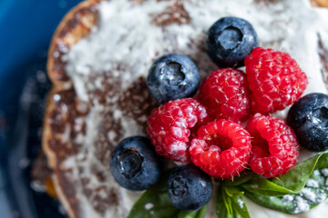 Pancakes with blueberries and raspberries with white sauce and Basil leaf. A sweet Breakfast. Close up.