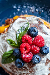 Pancakes with blueberries and raspberries with white sauce and Basil leaf. A sweet Breakfast. Close up.