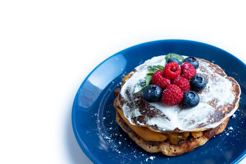 Pancakes with blueberries and raspberries with white sauce and Basil leaf. A sweet Breakfast