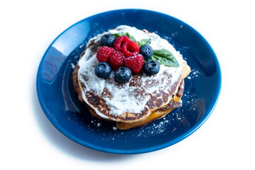 Pancakes with blueberries and raspberries with white sauce and Basil leaf. A sweet Breakfast