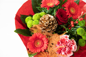 Strauß zu Weihnachten als Geschenk mit roten und grünen Pflanzen und Blumen und einem goldenen Zapfen