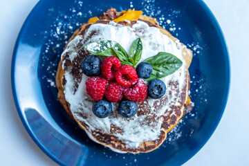 Pancakes with blueberries and raspberries with white sauce and Basil leaf. A sweet Breakfast