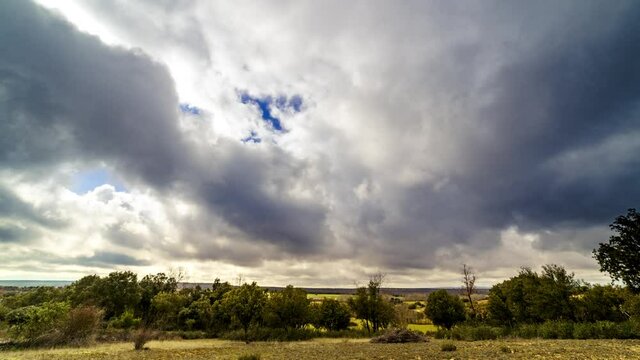 Timelapse nubes. Paisaje con cielo nublado y nubes corriendo r&aacute;pido hacia c&aacute;mara en campo con &aacute;rboles y plantas.