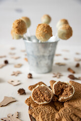 Kuchen am Stiel mit einer Füllung aus Spekulatius und Mascarpone umhüllt mit weißer Schokolade auf einem weißen Tisch aus Holz im Winter zu Weihnachten