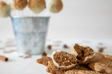 Kuchen am Stiel mit einer Füllung aus Spekulatius und Mascarpone umhüllt mit weißer Schokolade auf einem weißen Tisch aus Holz im Winter zu Weihnachten
