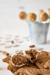Kuchen am Stiel mit einer Füllung aus Spekulatius und Mascarpone umhüllt mit weißer Schokolade auf einem weißen Tisch aus Holz im Winter zu Weihnachten