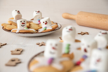 Plätzchen mit Marshmallows, Zuckerguss und Schokolinsen die aussehen wie geschmolzene Schneemänner auf Tellern zur Weihnachtszeit