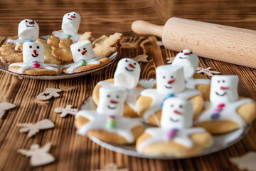 Plätzchen mit Marshmallows, Zuckerguss und Schokolinsen die aussehen wie geschmolzene Schneemänner auf Tellern zur Weihnachtszeit