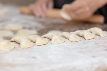 Woman rolls the dough with a rolling pin on the table.