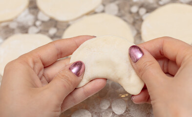 The girl sculpts dumplings from dough.