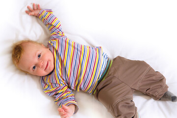 Cheerful baby boy lies on a white background and smiles.