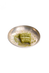 world famous baklava making in Gaziantep, pistachio wrap in metal plate on white background.The Turkish name of this dessert variety is fıstıklı sarma.