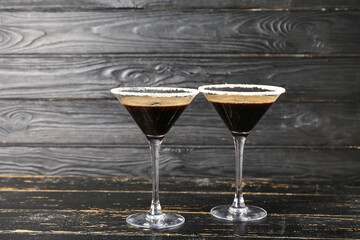 Two glasses of tasty espresso martini cocktail on wooden background