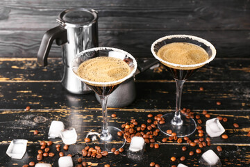 Two glasses of tasty espresso martini cocktail on wooden background