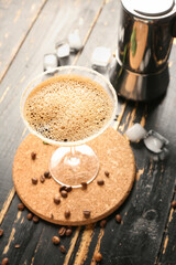 Glass of tasty espresso martini cocktail and geyser coffee maker on wooden background