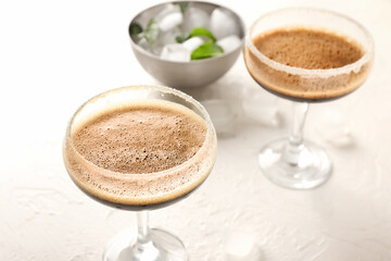 Two glasses of tasty espresso martini cocktail on light background