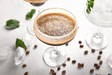 Glasses of tasty espresso martini cocktail on light background