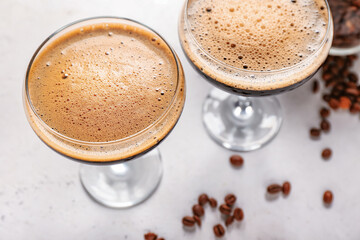 Two glasses of tasty espresso martini cocktail on light background