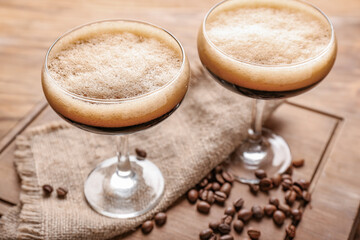 Two glasses of tasty espresso martini cocktail on wooden board