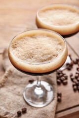 Two glasses of tasty espresso martini cocktail on wooden board