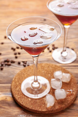 Two glasses of tasty espresso martini cocktail with ice on wooden table