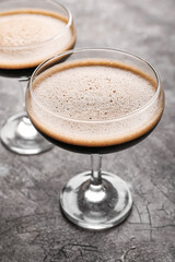 Two glasses of tasty espresso martini cocktail on grunge background