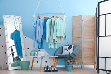 Rack with autumn clothes in interior of modern room