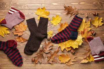 Warm socks and autumn leaves on wooden background