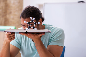 Young male student physicist studying molecular model at home
