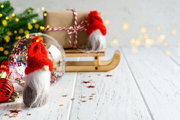 Christmas or New Year composition with gnomes (elf), gift box, decorations, on white rustic wooden background. Festive, winter, concept.