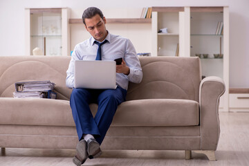Young male employee working from home in pandemic concept