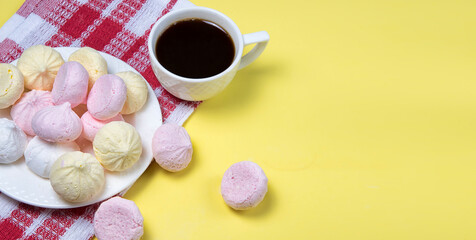 Obraz na płótnie Canvas Small homemade meringue kisses. Banner with meringue cookies and coffee cup on red tablecloth and yellow background. Copyspace.