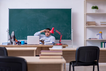 Young male teacher in front of green board