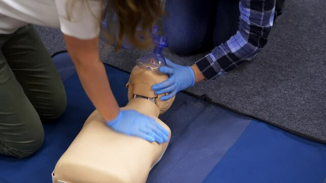 Dummies for medics used for first aid trainings. Oxigen masks near medical dolls. Two medics train on courses.