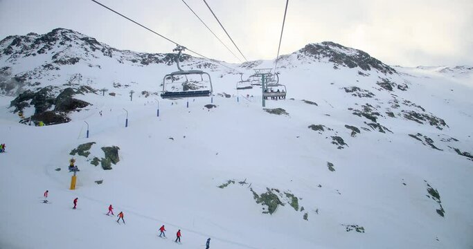 View of a chairlift in a mountain, with snow under the chair lift, with sunlight in the sky. Perfect leisure activty in a beautiful mountain landscape 4K