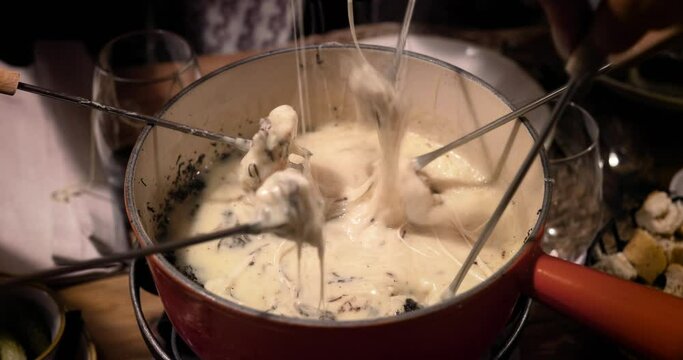 Close up od a cheese fondue. We can see the bread soak in the melted cheese. Perfect meal with friends 4K
