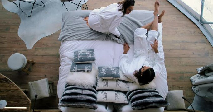 Couple lying in a bed and hugging each other. Attractive man and woman relaxing in a white bed - view from above the bed 4K