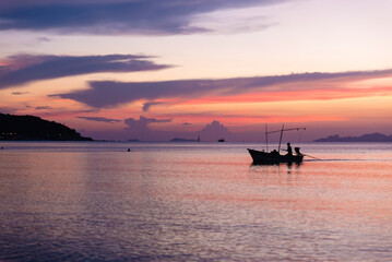 Obraz premium fisherman on a boat at sunrise, beautiful sunset on Koh Samui island in Thailand, yoga and meditation, sun over the horizon, serenity on the beach