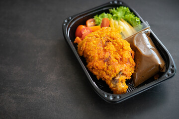 Chicken Chop and fries with  Black Pepper sauce and vegetables. in a take away container.