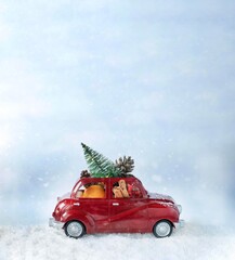 Christmas red car carying christmas tree and decorations. Christmas card concept Vertical imge with copy space