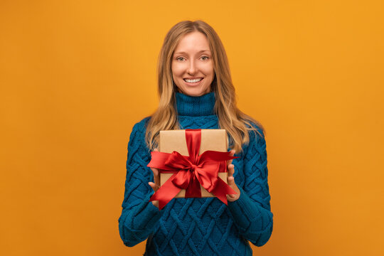 Image of charming young woman smiling and holding gift with red ribbon. New Year, Birthday, Holiday concept