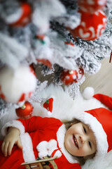Merry bright christmas. Lovely baby enjoy christmas. Childhood memories. Santa girl little child celebrate christmas at home. Family holiday. Girl cute child cheerful mood play near christmas tree.
