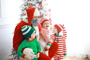 Santa Claus sitting with little cute elves over Christmas background. Time of miracles. Gifts from Santa Claus.