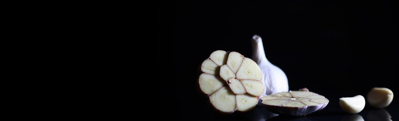 Fresh garlic clove on black background. Garlic is rich in vitamins, useful spring, good spices. Garlic sliced on a dark background. Raw sliced garlic.