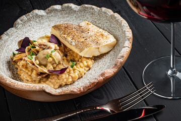 risotto with white fish on black background