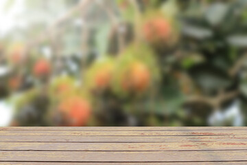 old wooden table top for place products and blurred Rambutan garden background