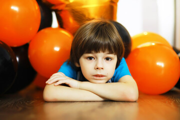Fototapeta na wymiar Portrait of a small child lying on the floor in a room decorated with balloons. Happy childhood concept.