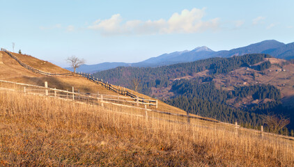 Fototapeta premium Autumn mountain landscape, wooden fence on mountain slope, mountain Homyak on the horizon. Ukraine, Carpathians.