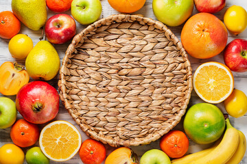 Fresh fruits background. Food photography different fruits and empty wicker tray on wooden white background.Flat lay.