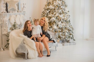 Obraz na płótnie Canvas Christmas family scene, two women with a child, happy moms, New year time